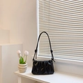 Minimalist black pleated hobo bag with knotted shoulder strap detail on a white surface - Black