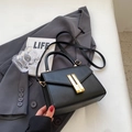 Vintage black crossbody square bag with grainy texture and golden buckle on grey suit - Black