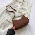 Brown quilted crescent shoulder bag with gold chain strap on white blazer texture - Brown