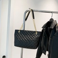 Glänzende schwarze Stepp-Tasche mit goldener Kette auf einem silbernen Ständer - Schwarz