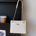 Elegante witte gewatteerde schoudertas met gouden draaisluiting en golvend patroon - Off-wit