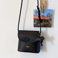 Minimalist black lychee leather crossbody bag with braided pendant and gold logo - Black