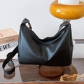 Minimalist black PU leather hobo bag with large capacity and metal zipper on wooden table - Black