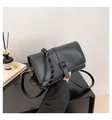 Detalle del bolso bandolera minimalista en cuero negro mate con asa trenzada decorativa - Negro