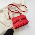 Bolso bandolera rojo de cuero sintético con hebilla dorada sobre un blazer de moda - Rojo