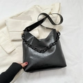 Borsa tote in morbida pelle nera con catena decorativa su un blazer avorio - Nero