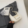 Bolso de media luna blanco con hebillas doradas sobre una chaqueta gris - Blanco Roto