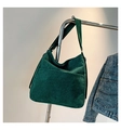 Dettaglio della borsa tote in velluto a coste verde scuro appesa con giacca di jeans - Verde