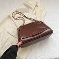 Bolso de hombro de cuero marrón oscuro con cadena dorada sobre un blazer crema - Marrón