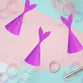 Three purple glitter mermaid tail party hats with elastic bands on colorful backdrop - Purple Glitter Mermaid Tail Paper Hat