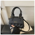 Detail of black quilted leather crossbody bag featuring gold lettering and metal clasp - Black
