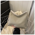 Detail of light olive leather tote with white trim and adjustable strap on a metal rack - Gray