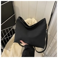 Detail of a black minimalist tote bag with adjustable strap and gold hardware in a basket - Black