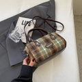 Grün-braune Karo-Zylindertasche mit Ledergriffen auf schickem Retro-Hintergrund - Hellgrün Kariert