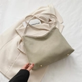 Olive green shoulder bag with cream trim and gold rivets on a beige blazer background - Gray