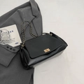 Classic black leather chain shoulder bag with gold hardware on a grey blazer - Black