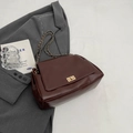 Deep brown vintage shoulder bag with golden chain strap and twist-lock on gray blazer - Coffee