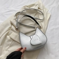 Silver crescent shoulder bag with a metallic love heart buckle on a white blazer - Silver