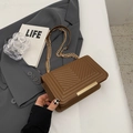 Sac à bandoulière matelassé marron avec chaîne dorée sur une veste grise chic - café