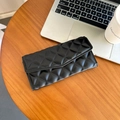 Elegante portafoglio nero trapuntato con cuciture a rombi su un tavolo di legno - Nero
