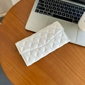 Elegante pochette in pelle bianca trapuntata con cuciture a rombi su un tavolo - Bianco