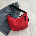 Minimalist red crescent crossbody bag with adjustable black strap on denim background - Red