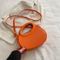 Modern orange dumpling bag with vertical textured stripes and circular cutout handles - Orange