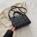 Detalle del bolso acolchado negro con textura de piel sintética y hebilla dorada fina - Negro