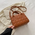 Bolso cuadrado pequeño acolchado marrón caramelo con asa y correa en un entorno casual - Marrón