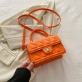 Bright orange quilted crossbody bag with a gold turn-lock buckle and top handle - Orange