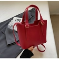 Gros plan sur un sac cabas en cuir grainé rouge vif avec des anneaux dorés chics - Rouge