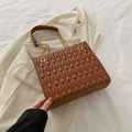 Brown quilted leather tote bag with gold chain strap placed on a stylish beige blazer - Brown