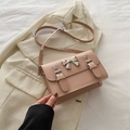 Elegante borsa a tracolla rosa cipria con fiocco su sfondo di giacca beige raffinata - Rosa