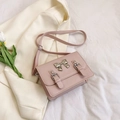 Pale pink crossbody square bag featuring a silver metal bow and adjustable leather strap - Pink