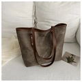 Detalle del bolso tote vintage café con tachuelas metálicas sobre fondo de seda blanca - Marrón