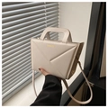 Close-up of beige handbag featuring geometric V-fold design and gold fashion text - Off White