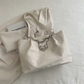 Minimalist cream white tote bag featuring decorative silver chain and metallic bow pendant - Off White