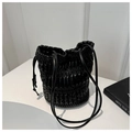 Detail of black pleated bucket bag with drawstring closure and glossy PU leather texture - Black
