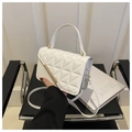 Close-up of white quilted handbag with golden bar hardware and luxury prop book background - White