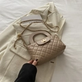 Sac beige matelassé avec fermoir doré posé élégamment sur une veste blanche - Kaki