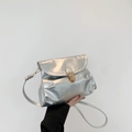 Silver metallic pleated shoulder bag with gold clasp shown in a minimalist studio setting - Silver