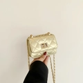 Mini quilted gold chain bag with metallic clasp closure shown in hand - Gold