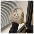 Detailed view of cream bow-decorated crossbody bag with elegant diamond quilted pattern - White