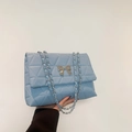 Light blue quilted crossbody bag featuring a silver metal bow and chain strap detail - Blue