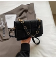 Detail of black quilted chain bag with gold accents shown in a modern lifestyle setting - Black