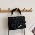 Quilted black leather handbag with ruched handle and gold hardware on a minimalist background - Black