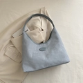 Minimalist light blue tote bag with matte texture and oval logo on beige jacket - Blue
