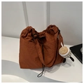 Macro detail of brown nylon drawstring bag fabric with a cute coffee cup plush charm - Orange With Pendant
