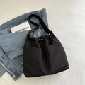 Black drawstring tote bag with dual front pockets and adjustable strap on denim background - Black without Pendant