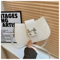 Primer plano de bolso bandolera blanco con textura rugosa y hebilla de lazo plateado - Blanco